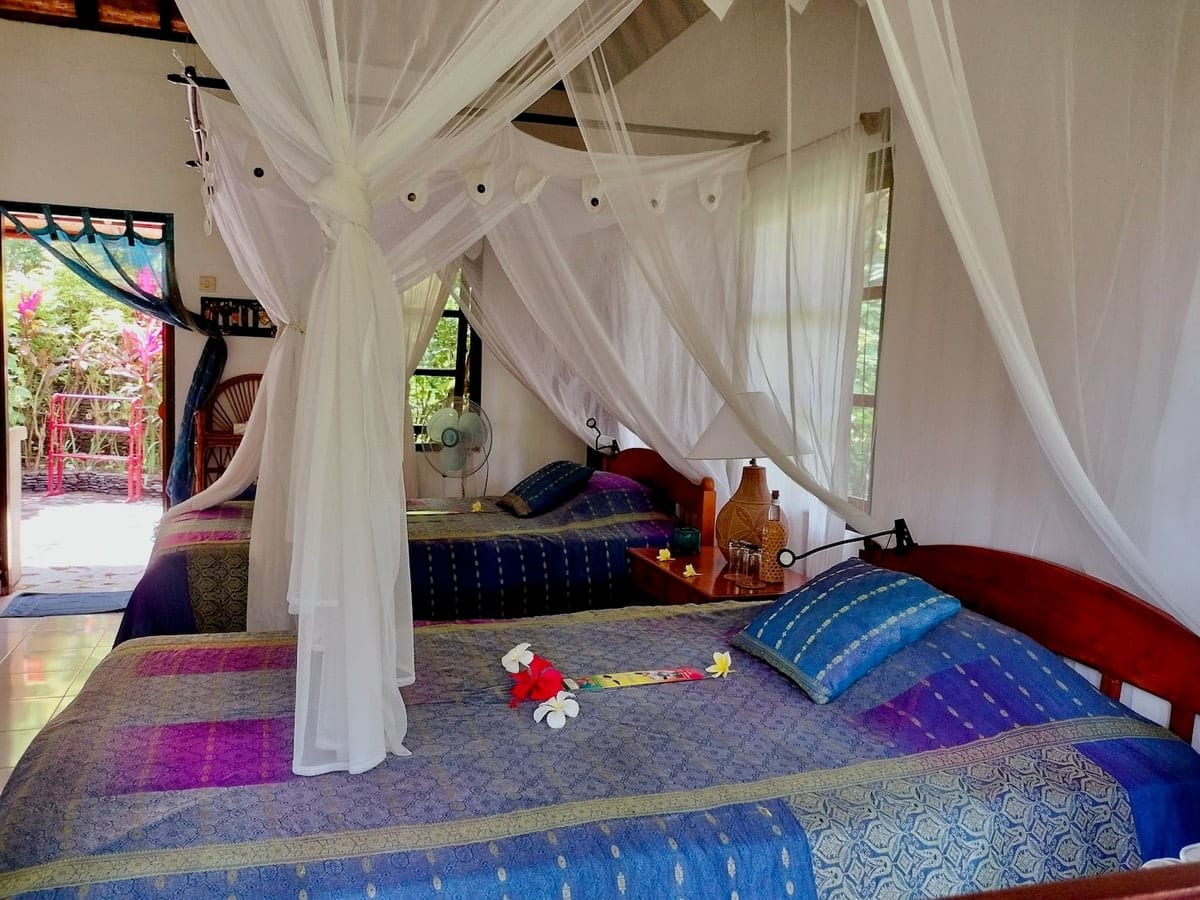 Im Innern eines Bali-Mandala-Bungalows — Himmelbett mit farbenfrohen balinesischen Stoffen