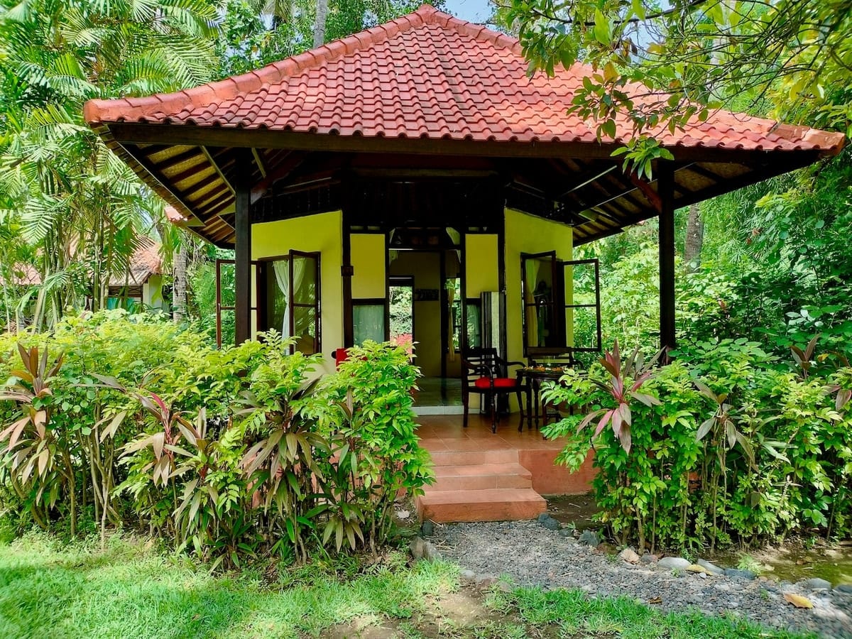 Garten-Bungalow im Bali Mandala — traditionelles rotes Ziegeldach, eingebettet in tropisches Grün