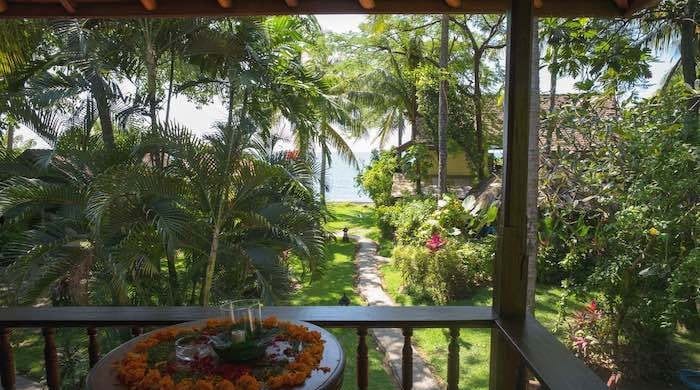 Blick von der Terrasse eines Bali-Mandala-Bungalows in den tropischen Garten und aufs Meer