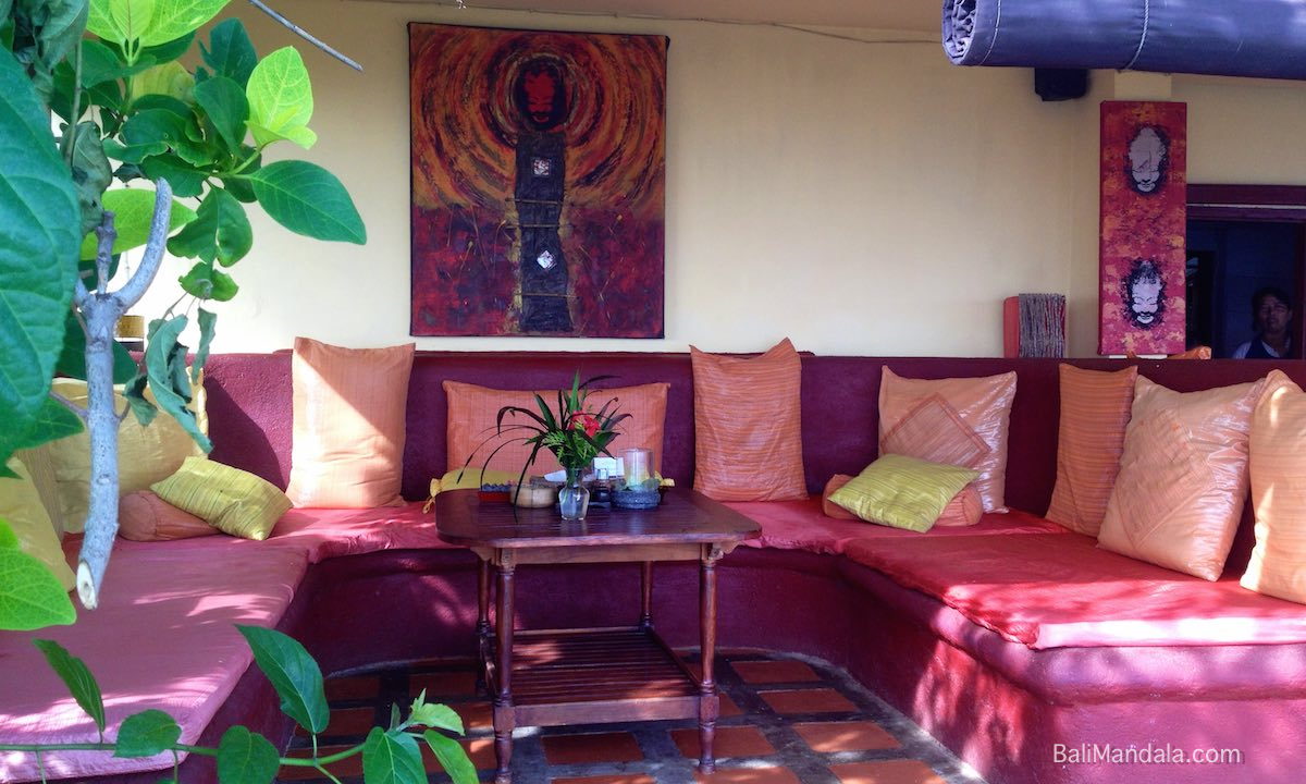 Die Bali-Mandala-Lounge — tiefrote Kissen und ein orangefarbenes Bali-Mandala-Gemälde